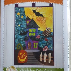 May include: Halloween Patch Wall Hanging pattern featuring a spooky house, a pumpkin, an owl, and a bat against a starry night sky. The pattern is from Shabby Fabrics.
