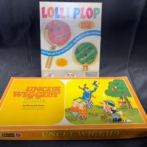 May include: Two vintage board games are displayed. The top game is "Lolli Plop," a skill game with a lollipop design. The bottom game is "The Uncle Wiggily Game" with colorful illustrations of cartoon characters.