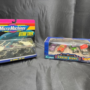 May include: Two toy car sets. One is a Micro Machines Star Trek set with miniature spacecraft. The other is a Hot Wheels Cruise Night set with four small cars in a blue box.