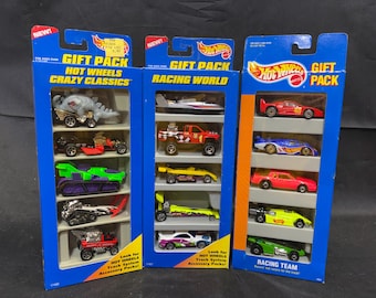 May include: Three Hot Wheels gift packs featuring die-cast toy cars. The Crazy Classics pack includes a dinosaur-themed vehicle, while the Racing World and Racing Team packs contain various sports cars, dragsters, and trucks in vibrant colors.