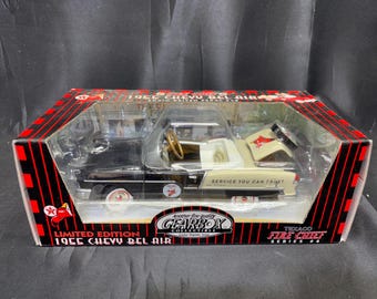 Op de afbeelding: Een limited edition 1955 Chevy Bel Air speelgoedauto in de originele doos. De zwart-crèmekleurige auto heeft de tekst "SERVICE YOU CAN TRUST" en een Texaco Fire Chief logo. De doos is rood en zwart met het Gearbox Collectibles logo.