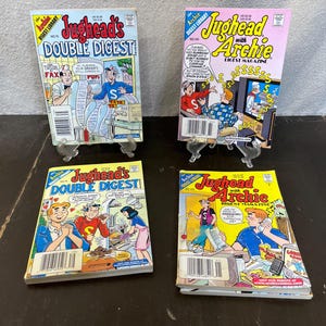 May include: Four comic books featuring the characters Jughead and Archie. The comic books are all in the Archie Comics Direct Library series. The covers feature the characters in various scenes, including Jughead eating a hamburger, Archie playing a video game, and Jughead and Archie cooking together.