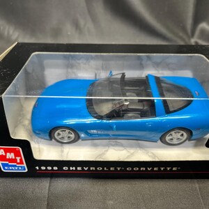 Puede incluir: Un coche modelo azul de un Chevrolet Corvette de 1996 en una caja de presentaci&oacute;n. El coche modelo es de un azul vibrante con ruedas plateadas y un interior negro. La caja tiene el logotipo de Chevrolet y el texto "1996 Chevrolet Corvette".