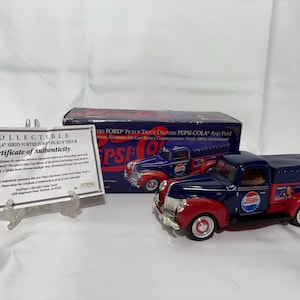 May include: A die-cast Pepsi-Cola Series 40s Ford pickup truck model in navy blue and red. The truck features the Pepsi logo and a canvas cover. A certificate of authenticity and the original box are also visible.