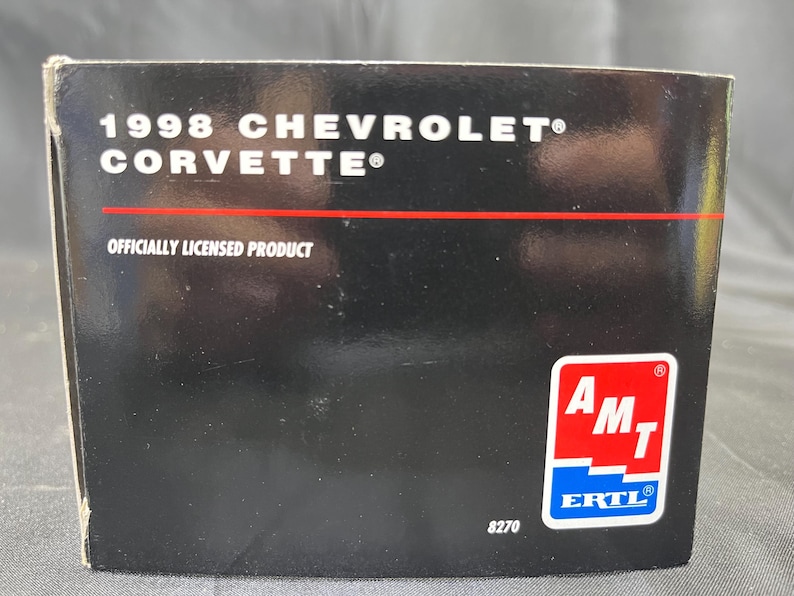 Puede incluir: Caja negra con el texto "1998 Chevrolet Corvette" y "Officially Licensed Product". Una l&iacute;nea roja separa el texto. La caja tiene un logotipo de AMT ERTL y el n&uacute;mero 8270.