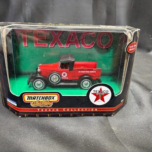 May include: A red Texaco 1930 Ford Model A truck toy in a Matchbox Collectibles box. The truck has black tires and a black roof. The box has the Texaco logo and the words "24 Hour Road Service."