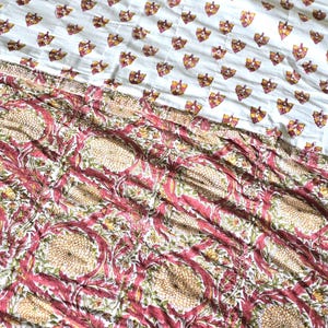 May include: A white and patterned textile featuring a repeating butterfly design in shades of yellow, orange, and burgundy. The lower portion showcases a floral pattern with burgundy and beige tones, creating a layered effect. This textile is suitable for bedding or home decor.