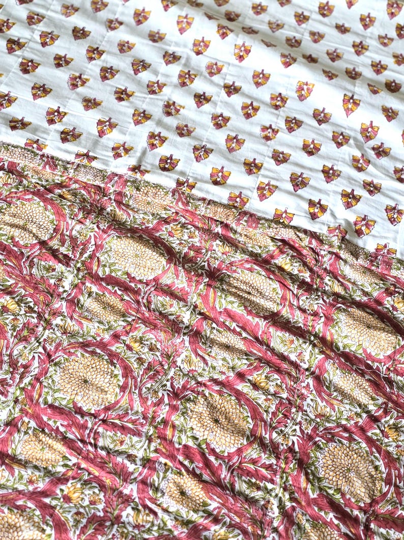 May include: A white and patterned textile featuring a repeating butterfly design in shades of yellow, orange, and burgundy. The lower portion showcases a floral pattern with burgundy and beige tones, creating a layered effect. This textile is suitable for bedding or home decor.