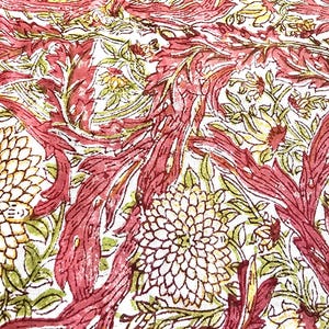 May include: Close-up of a fabric with a repeating floral pattern. The design features large, stylized flowers in cream and burgundy, with green and yellow accents. The background is white, and the overall effect is a vintage, botanical print.