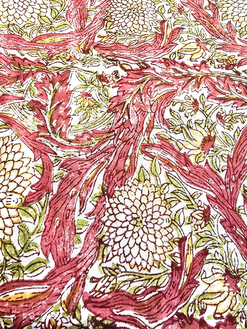 May include: Close-up of a fabric with a repeating floral pattern. The design features large, stylized flowers in cream and burgundy, with green and yellow accents. The background is white, and the overall effect is a vintage, botanical print.