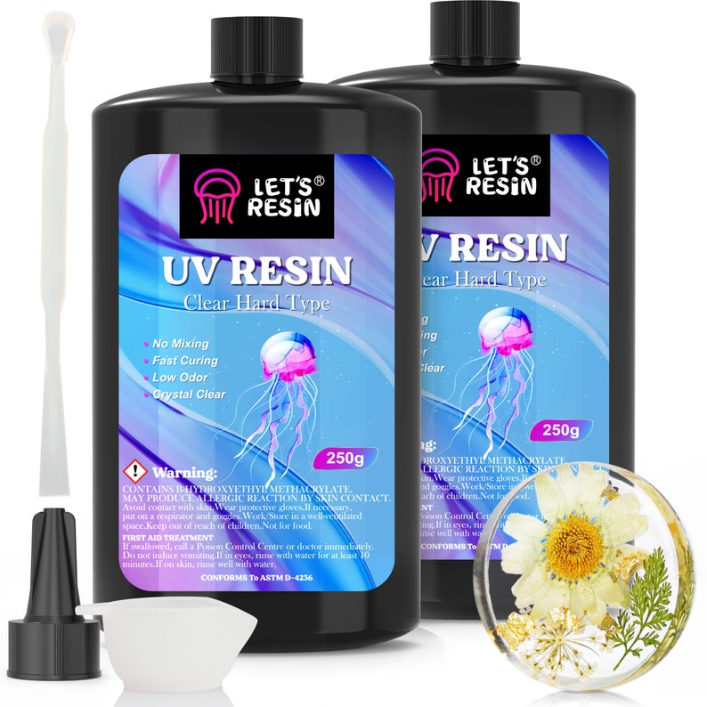 May include: Two 250g bottles of clear UV resin with a jellyfish graphic and the text "LET'S&reg; RESIN UV RESIN Clear Hard Type". The bottles are labeled with instructions and warnings. A clear resin project with a white flower is shown in the lower right corner.