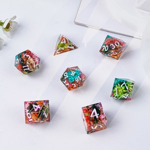 May include: Set of seven colorful dice with pressed flowers and white numbers. The dice are a d4, d6, d8, d10, d12, and two d20s.
