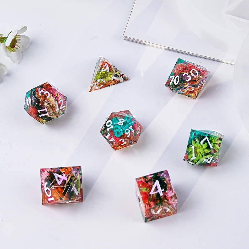 May include: Set of seven colorful dice with pressed flowers and white numbers. The dice are a d4, d6, d8, d10, d12, and two d20s.