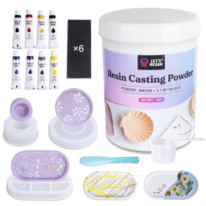 May include: Resin casting kit with a 1 kg container of resin powder, six tubes of acrylic paint, a measuring cup, a stirring stick, and four silicone molds. The molds are in various shapes and sizes, including a round tray, an oval tray, and a small ring mold. The molds are decorated with a purple and white floral pattern.