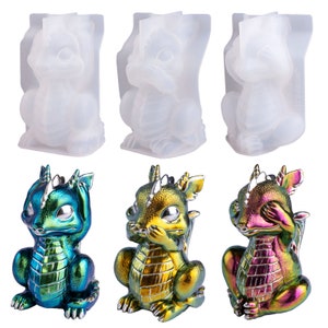 May include: Three silicone molds for making dragon figurines. The molds are clear and show the details of the dragon figurines. The dragon figurines are green, gold, and pink with iridescent finishes. The dragon figurines are in the "See No Evil, Hear No Evil, Speak No Evil" pose.