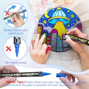 May include: A set of black acrylic paint markers with blue tips. The markers have the words "Acrylic Paint Marker" printed on the side. The image shows a hand holding a marker and shaking it, and another hand using the marker to color a drawing of a city with a UFO in the sky. The text "Warm Tips: Please close your pen cap after use each time. Protect the pen to prevent ink from drying out." is printed at the bottom of the image.