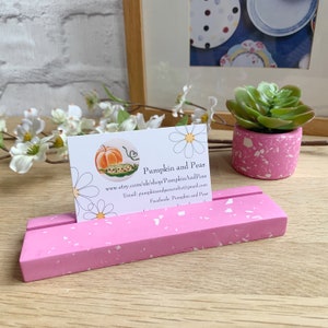 May include: Pink and white speckled concrete business card holder with a white business card that says "Pumpkin and Peas" with a website, email, and Facebook page listed.