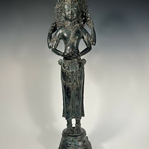May include: A bronze statue of a four-armed deity with a crown and a serene expression. The statue is standing on a square base and is in a meditative pose.