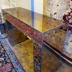 May include: A mirrored console table with a rectangular top and two legs. The table is decorated with a patterned fabric that is reflected in the mirror.