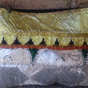 May include: A small, gold and silver embroidered pouch with a zipper closure. The pouch has a black, red, and green trim.