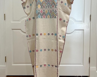 May include: A white cotton dress with colorful embroidered flowers and geometric patterns. The dress has a scoop neck and short sleeves.