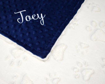 May include: A blue and white personalized blanket with the name "Joey" embroidered on the blue side. The white side has a paw print pattern.