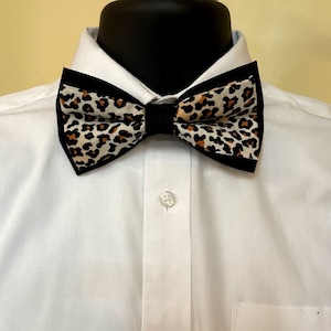 May include: A black bow tie with a brown and white leopard print pattern.