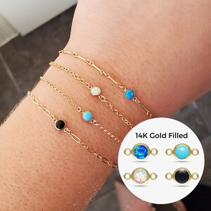 May include: Five gold-filled chain bracelets with different colored gemstone beads. The beads are turquoise, opal, and black. The image also shows a close-up of the beads in a circle with the text "14K Gold Filled".