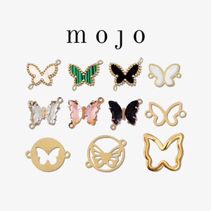 May include: A collection of butterfly-shaped charms in various designs and colors, including gold, green, black, and white. The word "mojo" is displayed in black text.