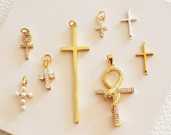 May include: A collection of gold and silver cross and ankh charms with various styles and embellishments, including pearl and crystal accents.
