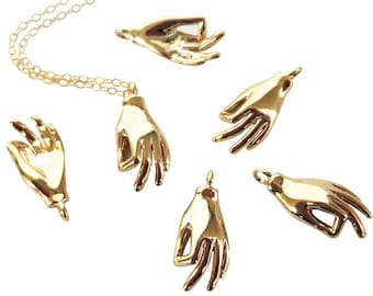 Könnte beinhalten: Eine goldene Halskette mit einem Hand-Anhänger. Es gibt fünf weitere Hand-Anhänger, die um die Halskette herum verstreut sind.