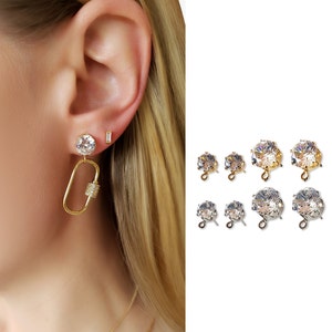 May include: A set of earring findings with a clear crystal stone and a gold or silver loop. The findings are available in two sizes.