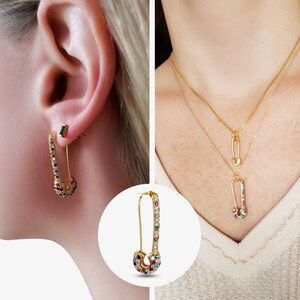 Puede incluir: Un par de pendientes de seguridad de oro con piedras preciosas de colores. Los pendientes se muestran en la oreja de una modelo. Los pendientes también se muestran sobre un fondo blanco.