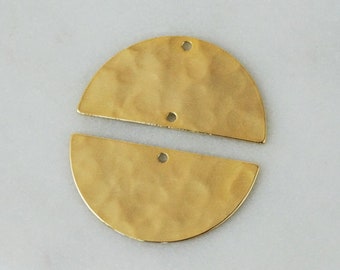 Op de afbeelding: Twee goudkleurige metalen onderdelen in de vorm van halve cirkels met een gehamerd, getextureerd oppervlak. Het bovenste stuk heeft twee kleine ronde gaatjes langs de platte rand, terwijl het onderste stuk één gaatje in het midden heeft.
