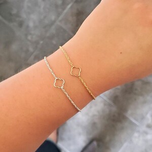 May include: Two delicate bracelets on a wrist. One is a gold rope chain with a four-leaf clover charm, the other is a silver rope chain with a four-leaf clover charm.  Styles shown: Priya rope chains, Asia clovers.
