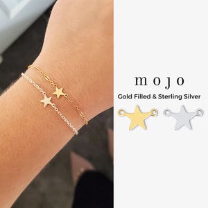 May include: A gold filled and sterling silver star charm bracelet. The bracelet is shown on a person's wrist. The charm is a simple star shape with a small loop on each side. The charm is available in both gold filled and sterling silver.