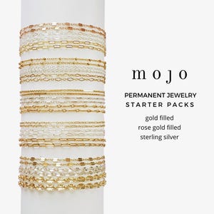 May include: An image showcasing permanent jewellery starter packs in gold filled, rose gold filled, and sterling silver. The image displays several delicate chain bracelets in various designs, stacked on a white cylindrical form. The word "mojo" is displayed in the image.