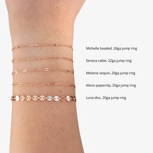 Puede incluir: Cinco pulseras de cadena de oro en una mu&ntilde;eca. Las pulseras est&aacute;n etiquetadas con sus nombres y calibre: Michelle beaded, 26ga jump ring; Seneca cable, 22ga jump ring; Melanie sequin, 20ga jump ring; Alexis paperclip, 20ga jump ring; Luna disc, 20ga jump ring.