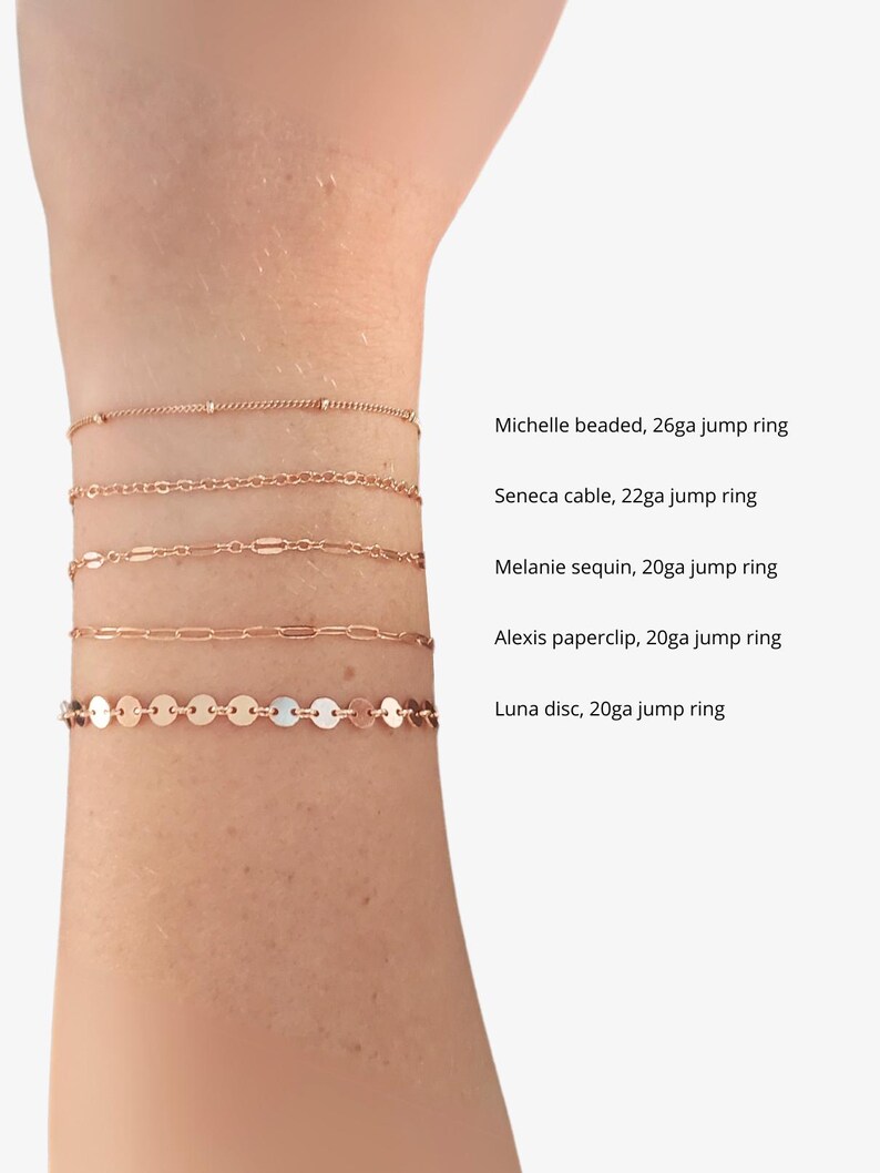 Puede incluir: Cinco pulseras de cadena de oro en una mu&ntilde;eca. Las pulseras est&aacute;n etiquetadas con sus nombres y calibre: Michelle beaded, 26ga jump ring; Seneca cable, 22ga jump ring; Melanie sequin, 20ga jump ring; Alexis paperclip, 20ga jump ring; Luna disc, 20ga jump ring.