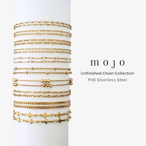 May include: A collection of gold-toned PVD stainless steel chains displayed on a white cylinder. The chains feature various link styles including cable, curb, bead, and cross designs. Text on the right reads: mojo Unfinished Chain Collection PVD Stainless Steel.