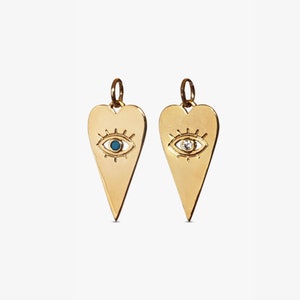 May include: Two gold heart-shaped pendants with an evil eye design. One pendant has a blue stone in the eye, and the other has a clear stone.