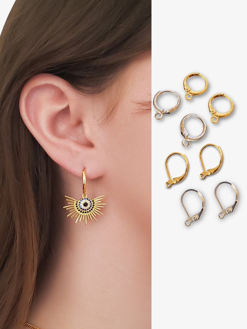 May include: Gold and silver earring hooks. The gold hook has a blue and black evil eye charm with gold rays around it.