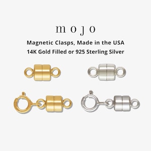 May include: Two magnetic clasps, one gold and one silver, with a lobster clasp on each side.  The text "mojo" is above the clasps, and the text "Magnetic Clasps, Made in the USA 14K Gold Filled or 925 Sterling Silver" is below the clasps.