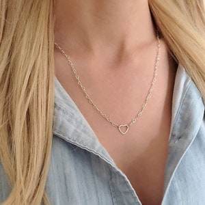May include: A silver heart chain necklace with a delicate open heart pendant. The chain is made of small, linked hearts.