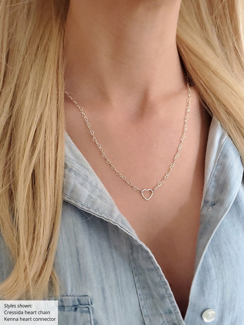 May include: A silver heart chain necklace with a delicate open heart pendant. The chain is made of small, linked hearts.