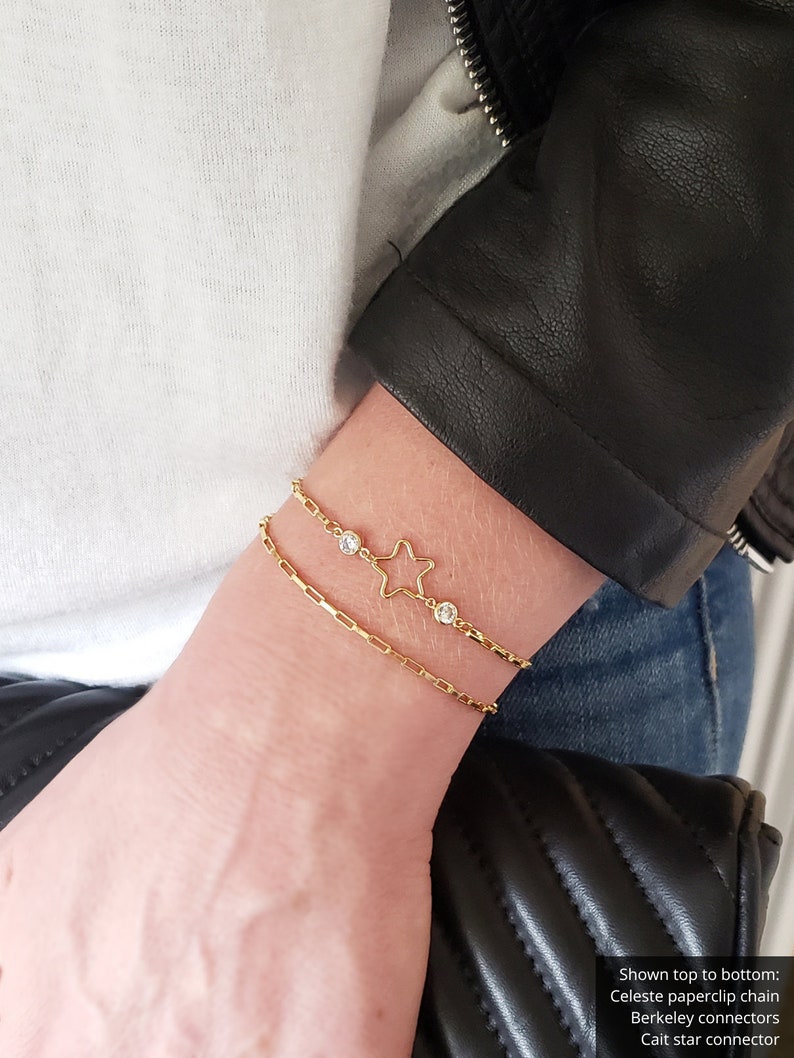 May include: Two gold bracelets with small clear stones. The top bracelet features a star charm. Shown top to bottom: Celeste paperclip chain, Berkeley connectors, Cait star connector.