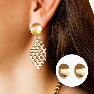 May include: Gold dangle earrings with a geometric pattern. The earrings feature a round top and a delicate, intricate design.