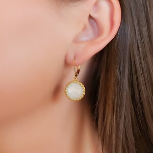 May include: Gold hoop earrings with a white pendant. The pendant is round and has a textured surface. Shown from top to bottom: Jolie hoop, Scarlett pendant.