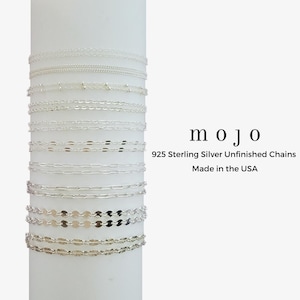 Puede incluir: Una colección de delicadas cadenas sin terminar de plata de ley 925. Las cadenas se muestran en una forma cilíndrica blanca. La imagen incluye el texto "mojo" y "925 Sterling Silver Unfinished Chains Made in the USA".