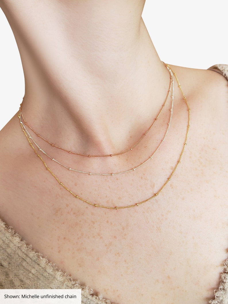 Puede incluir: Tres collares superpuestos con cuentas doradas, plateadas y de oro rosa. Los collares est&aacute;n superpuestos en el cuello de una persona.